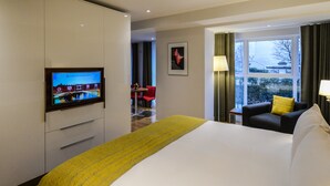 Una habitación de hotel con cama, televisión, escritorio y ventana con cortinas.