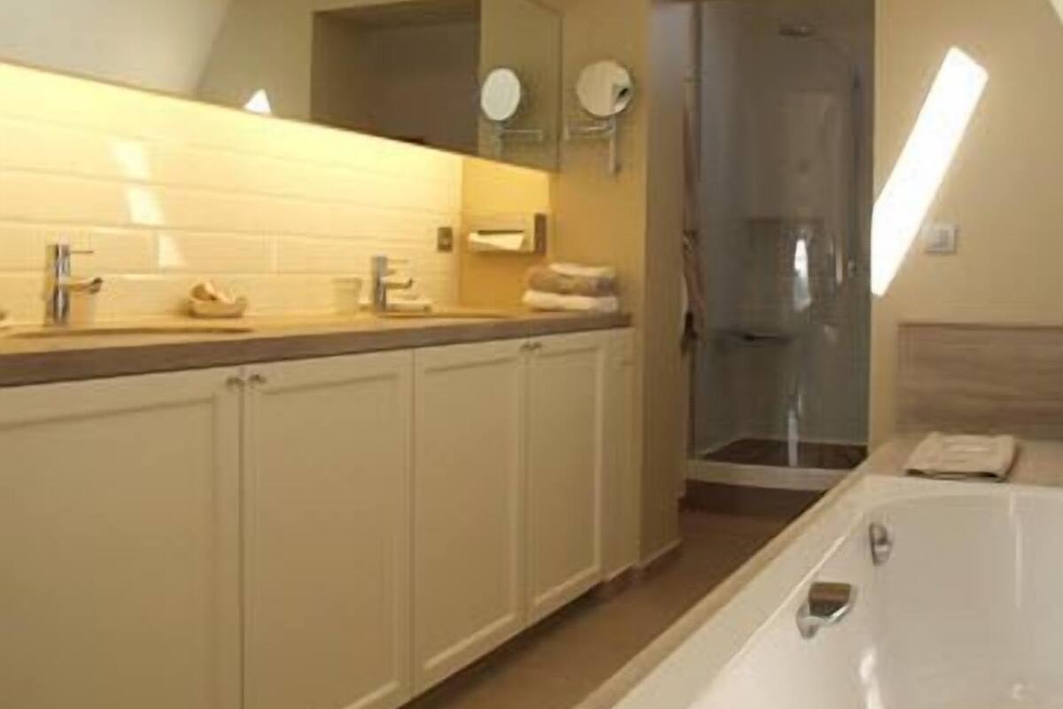 Een badkamer met een bad, douche en een wastafel met spiegel.