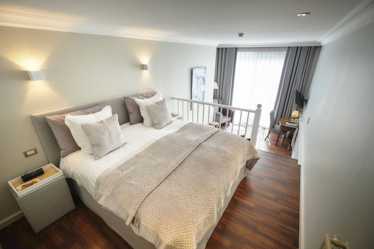 Een moderne hotelkamer met een groot bed, nachtkastjes, een bureau en een balkon met uitzicht.