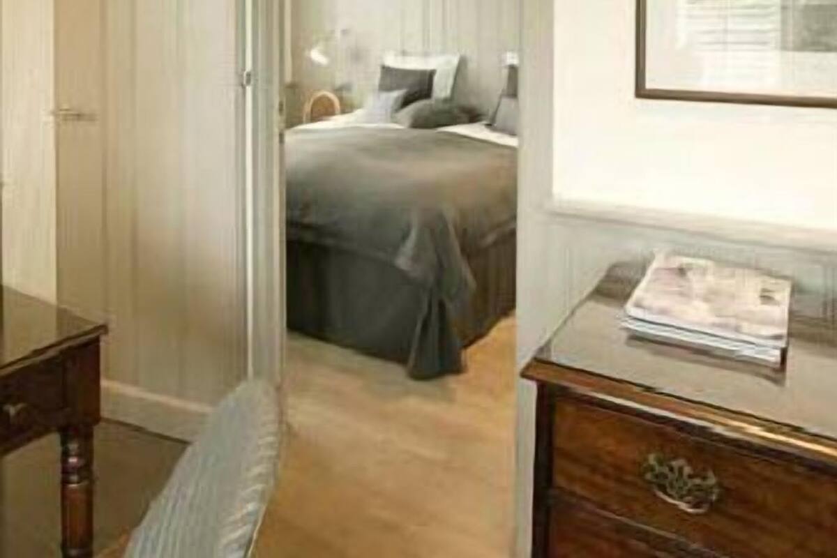 Een slaapkamer met een bed, een dressoir en een lijst met een foto aan de muur.