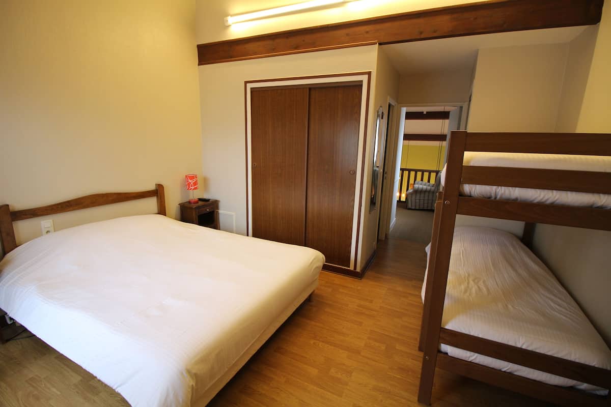 A bedroom with a single bed, a wooden bunk bed, a wardrobe, and a small bedside table.