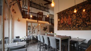 A restaurant with a bar area, high ceilings, and a staircase.