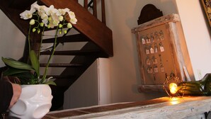 A staircase with wooden railings, a white vase with flowers, and a decorative lantern on a rustic shelf.