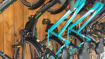 Un aparcaciclos con varias bicicletas, incluyendo una verde azulada y una negra, en una habitación de madera.