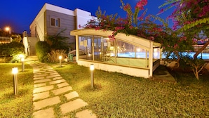 A modern building with a glass conservatory, a stone pathway, and a pool area. - Royal Palm Residence (Bodrum)