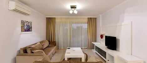 A modern living room with a sofa set, a coffee table, a TV on a stand, and a large window with curtains.