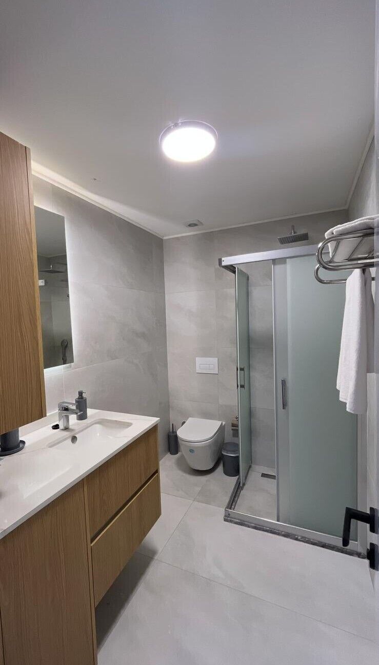 A modern bathroom with a shower, a sink, and a mirror.