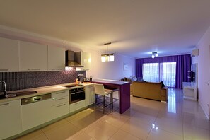 Una cocina moderna con una isla central, electrodomésticos integrados y un comedor con sofá y sillas.