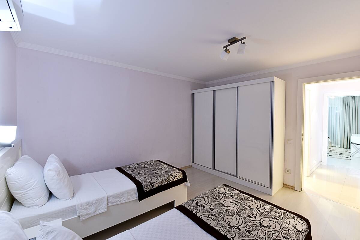 Un dormitorio con dos camas, un armario y una puerta que da a un balcón.