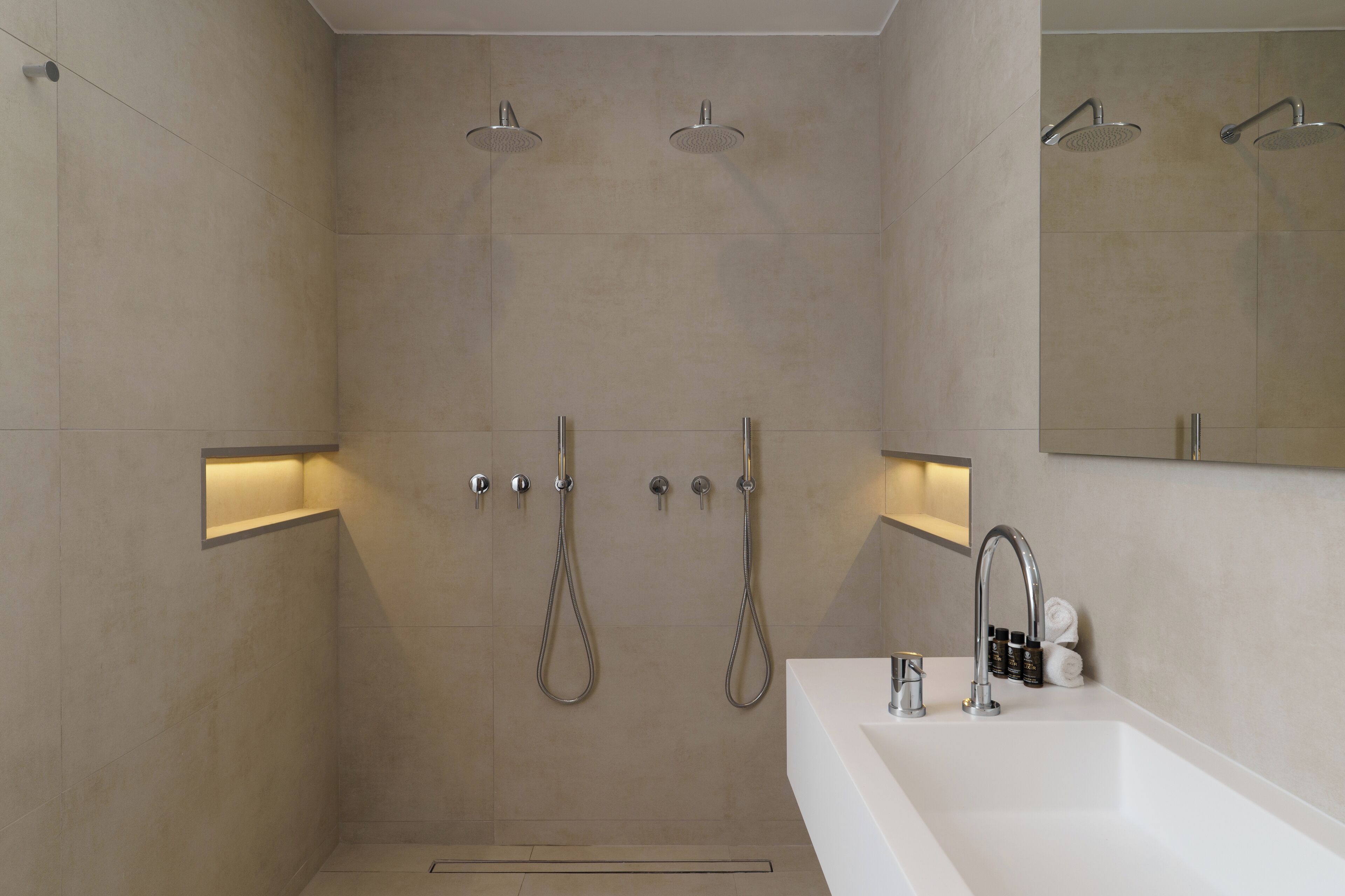 A modern bathroom with a large shower area, a separate sink, and a mirror above the sink.