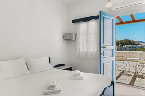 A hotel room with a bed, a bathroom, and a view of the city.