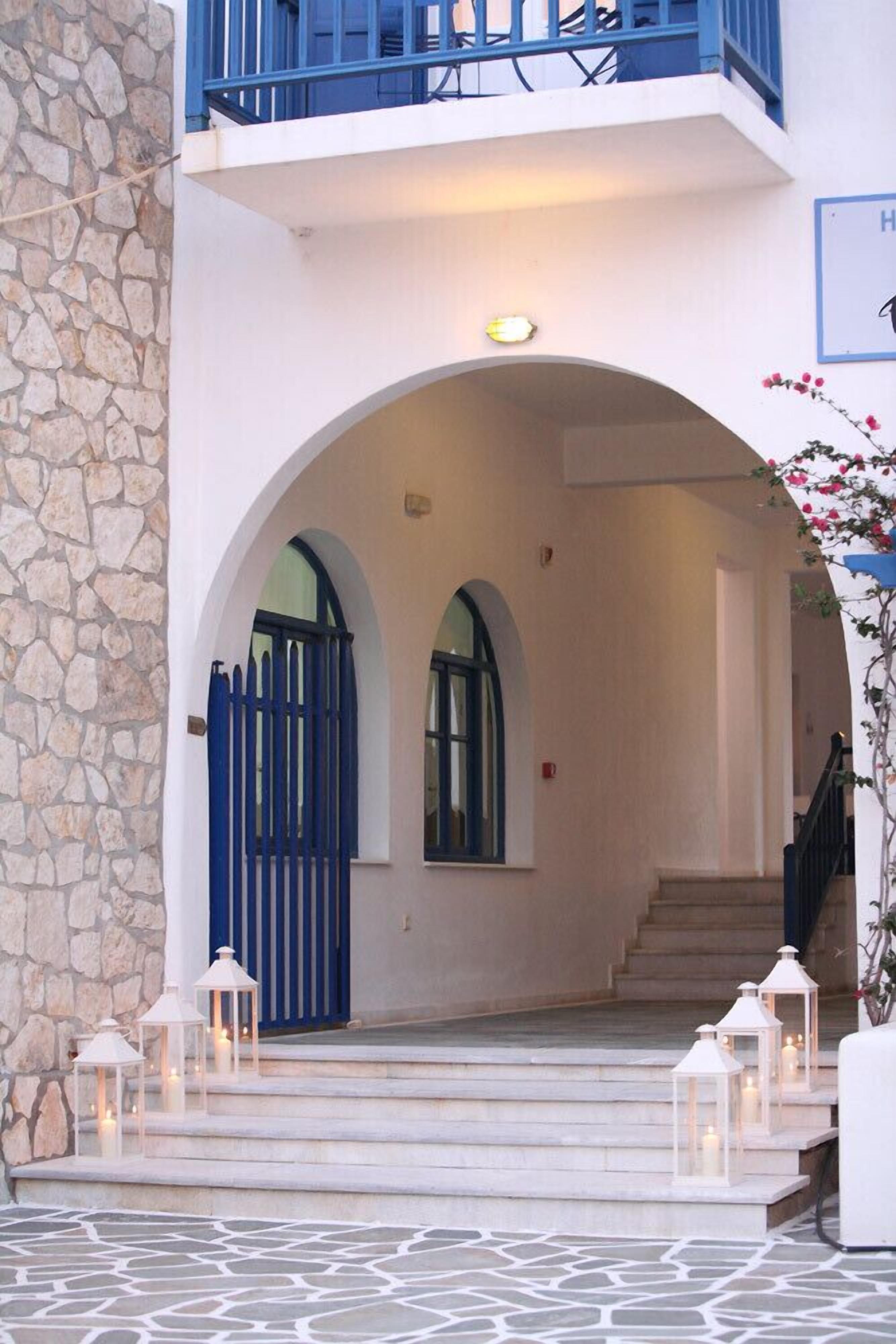 L’entrée d’un immeuble avec une façade en pierre, un portail bleu et des marches menant à un balcon.
