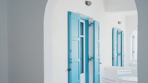 Una habitación con paredes blancas y puertas azules, que incluye una mesa y sillas blancas.