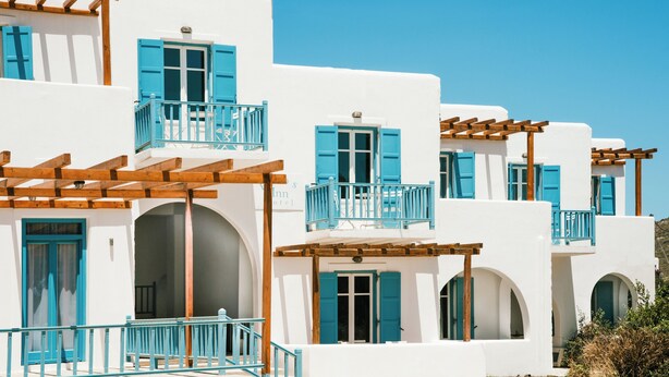 Un edificio blanco con contraventanas azules y balcones de madera.