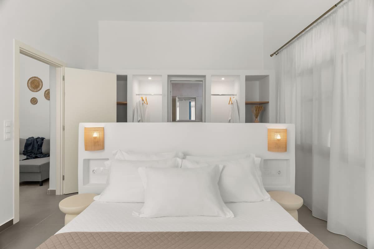 Una habitación de hotel moderna con una cama grande, mesitas de noche, un espejo y luces instaladas en la pared.