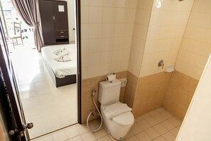 A small bathroom with a toilet, a shower area, and a bed visible through an open door. - Happy Fish Guesthouse (Patong)