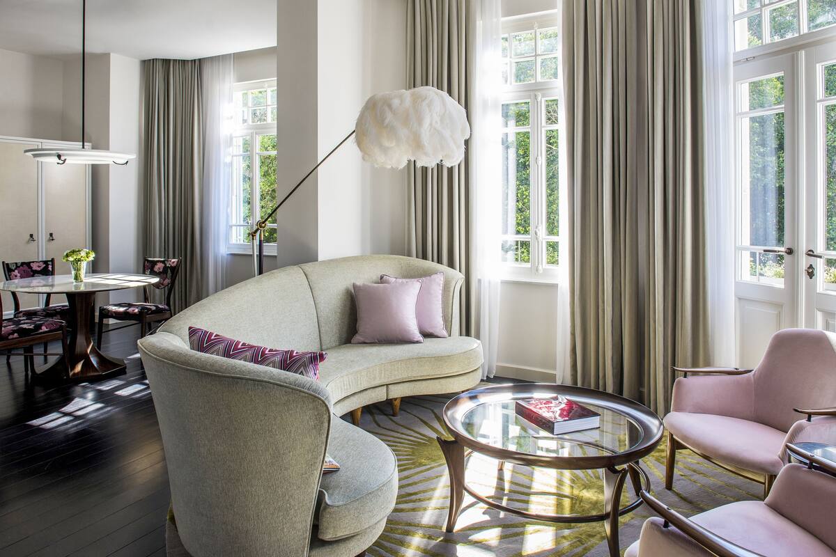 A modern living room with a curved sofa, a round coffee table, and a dining area with a table and chairs.