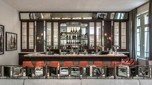 A bar area with a long counter, multiple seating options, and a mirrored wall. - The Norman Tel Aviv (Tel Aviv)