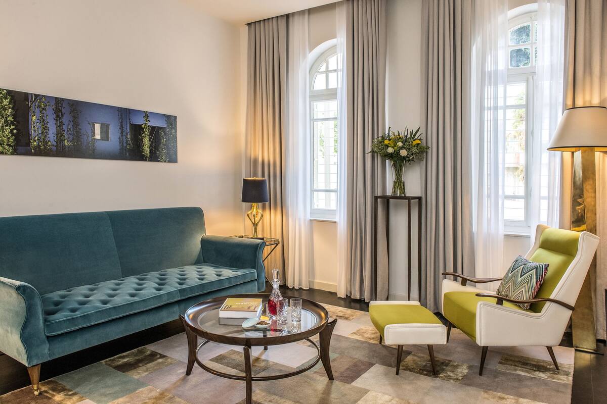 A living room with a teal sofa, a round coffee table, a green armchair, and a floor lamp.
