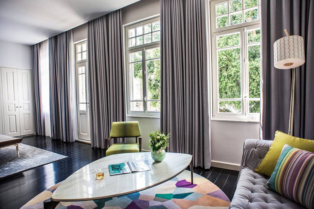 A modern living room with a sofa, a green chair, a coffee table, and a large window with curtains.