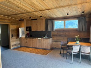 A compact kitchen with wooden cabinetry, a central island, and a dining area with a table and chairs.