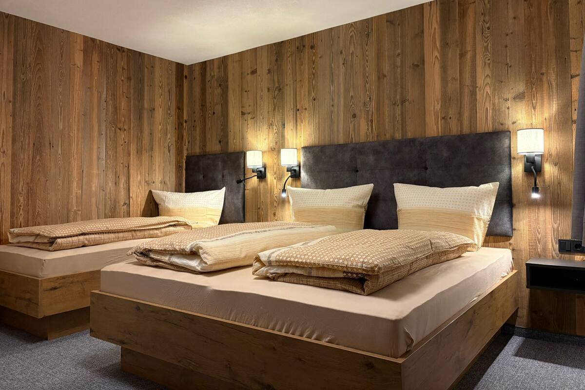Una cama doble con cabecera oscura, dos mesitas de noche y lámparas de pared.