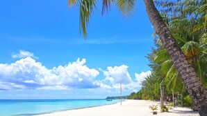 A beach with white sand, palm trees, and a clear blue sky. - DiveGurus Boracay Beach Resort (Boracay Island)