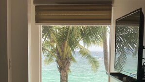 A room with a wooden table and chair facing a window with a view of the ocean and palm trees. - DiveGurus Boracay Beach Resort (Boracay Island)