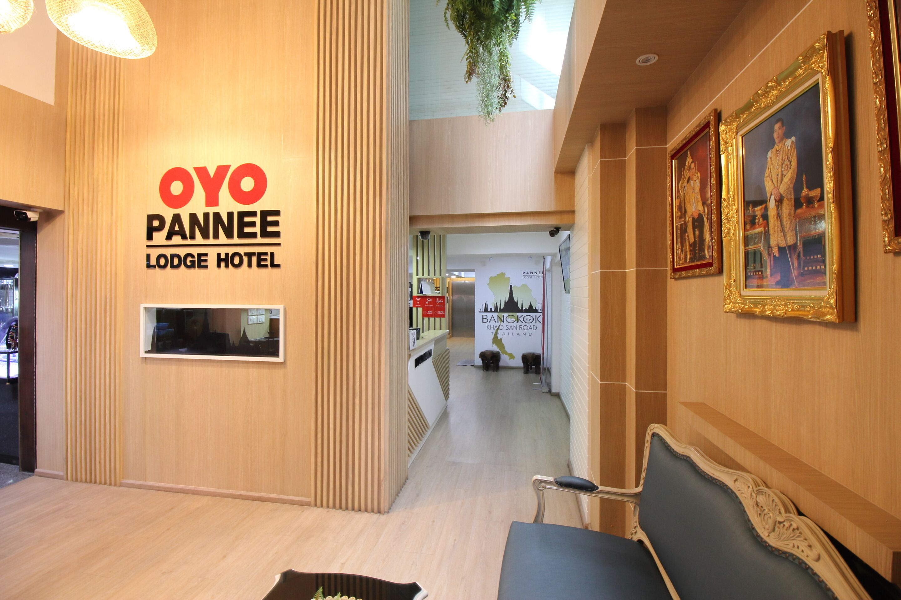 A reception area of the OYO Panneree Lodge Hotel with a wooden interior, a reception desk, and framed pictures on the wall.