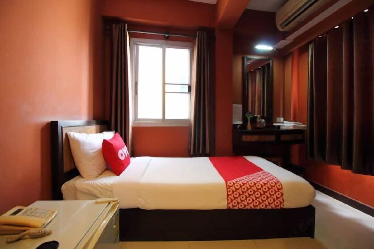 Een hotelkamer met een bed, een bureau, een telefoon en een raam met gordijnen.