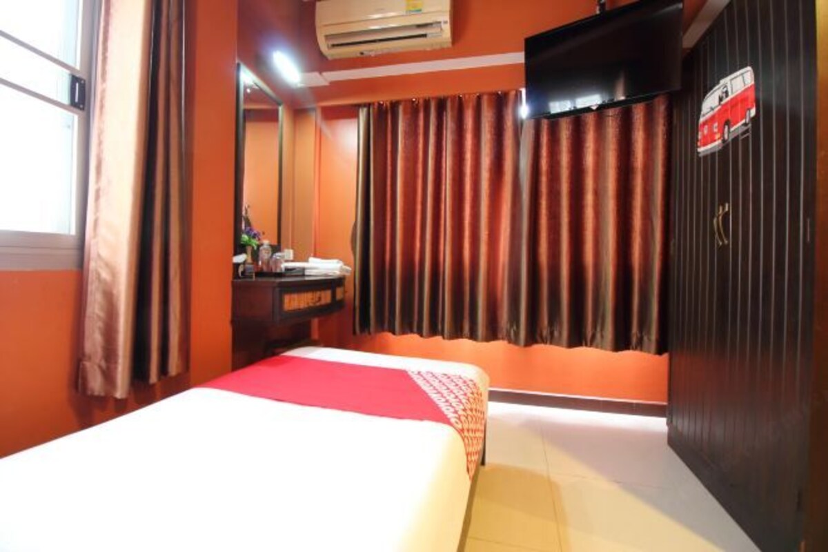 Een hotelkamer met een bed, een dressoir, een spiegel, een televisie en gordijnen.