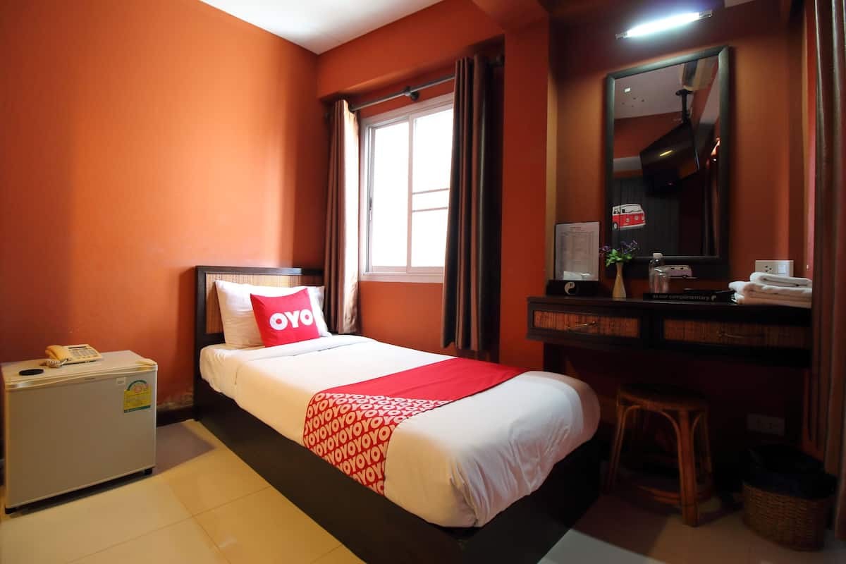 Een hotelkamer met een bed, een bureau, een spiegel, een raam en een kleine koelkast.
