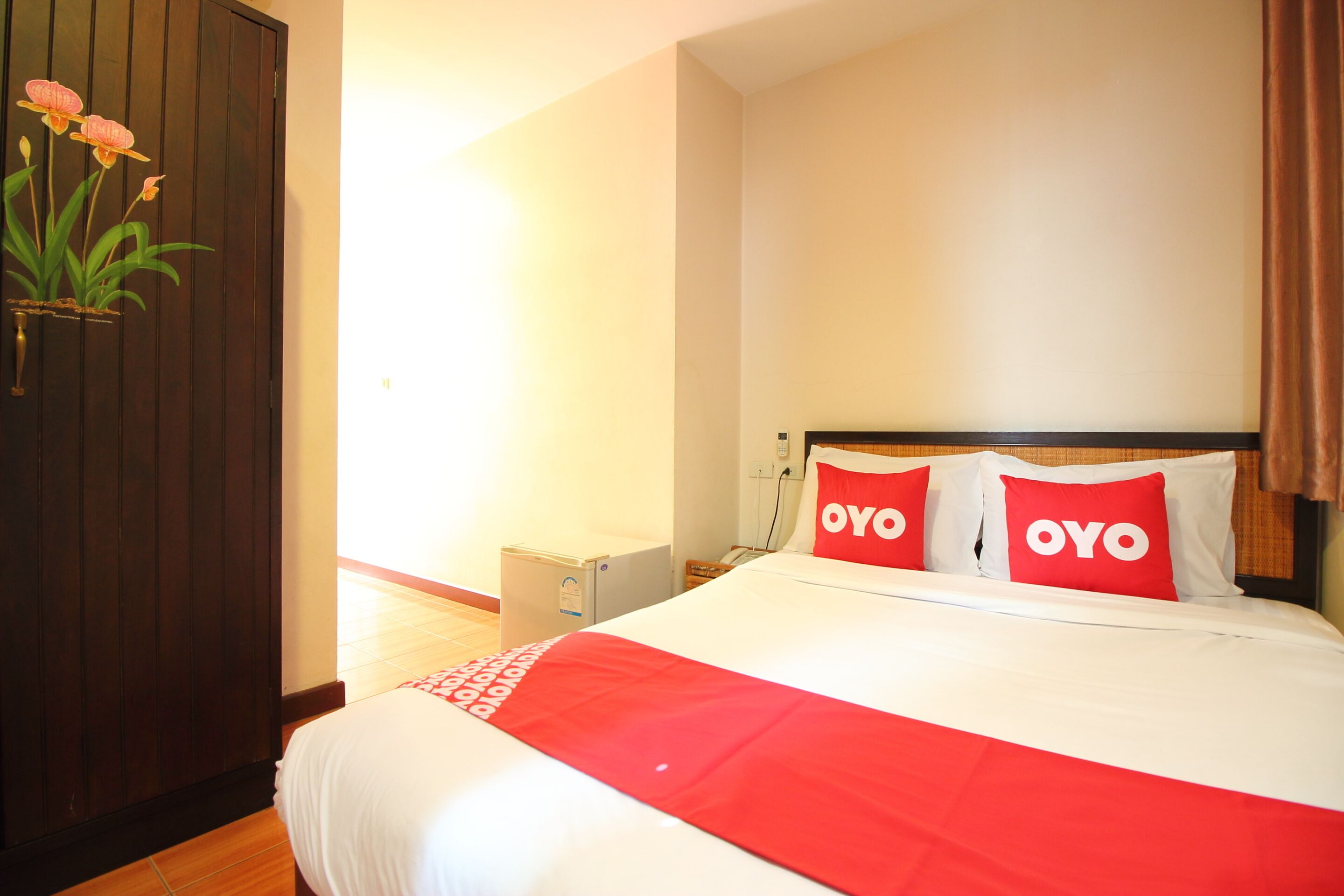 Une chambre d’hôtel avec un lit, deux oreillers sur lesquels est inscrit le mot « OYO », une petite table de chevet et une commode.
