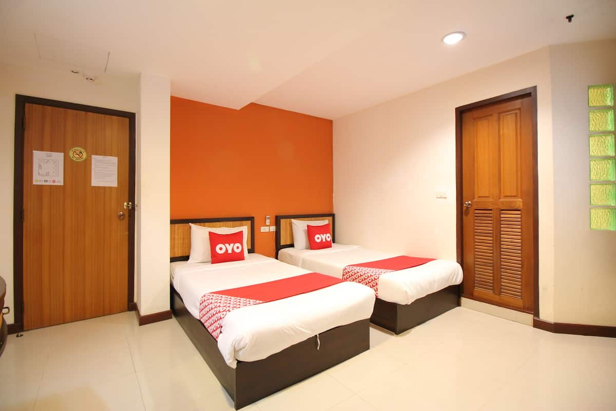 Een hotelkamer met twee bedden, oranje wanden, houten deuren en een betegelde vloer.