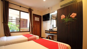 Une chambre d’hôtel avec deux lits, un bureau, une télévision et une armoire décorée de motifs floraux.