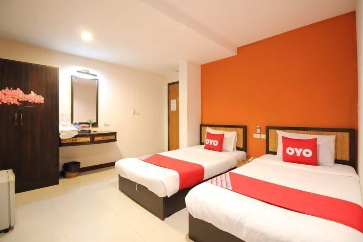 Een hotelkamer met twee bedden, een houten garderobe, een spiegel en een wastafel.