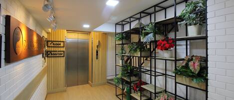 A hallway with a wooden floor, a metal staircase, and a wall-mounted plant shelf.
