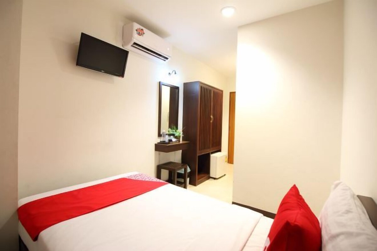 Una habitación de hotel con cama, escritorio, espejo y televisor.