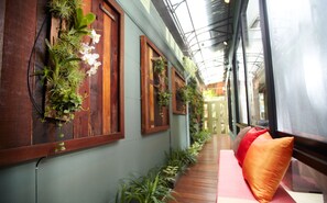 A corridor with wooden walls, potted plants, and a bench with cushions. - Super OYO 484 Pannee Residence Khaosan (Sha Plus) (Bangkok)