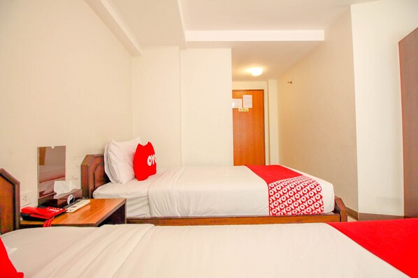 A hotel room with two beds, a wooden nightstand, a desk with a telephone and a red bag, and a door with a sign. - Super OYO 484 Pannee Residence Khaosan (Sha Plus) (Bangkok)