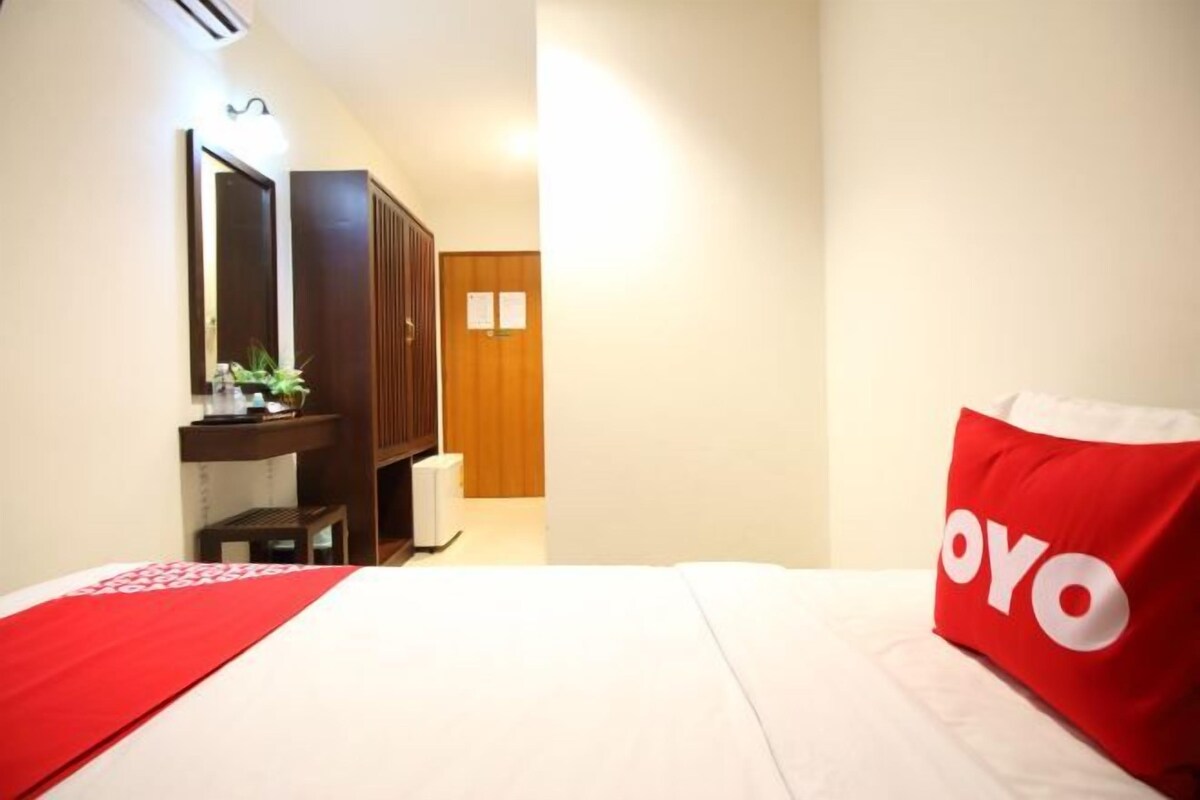 A hotel room with a bed, a desk, a mirror, and a wardrobe.