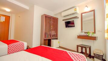 A hotel room with two beds, a TV, an air conditioner, a mirror, a small table, and a trash bin.
