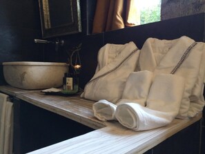 A bathroom with a large basin, towels, and a small candle on the counter. - Sevenmaze Charming House (Bari)