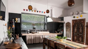 A modern kitchen with a central island, a dining area with wooden furniture, and a decorative door. - Sevenmaze Charming House (Bari)