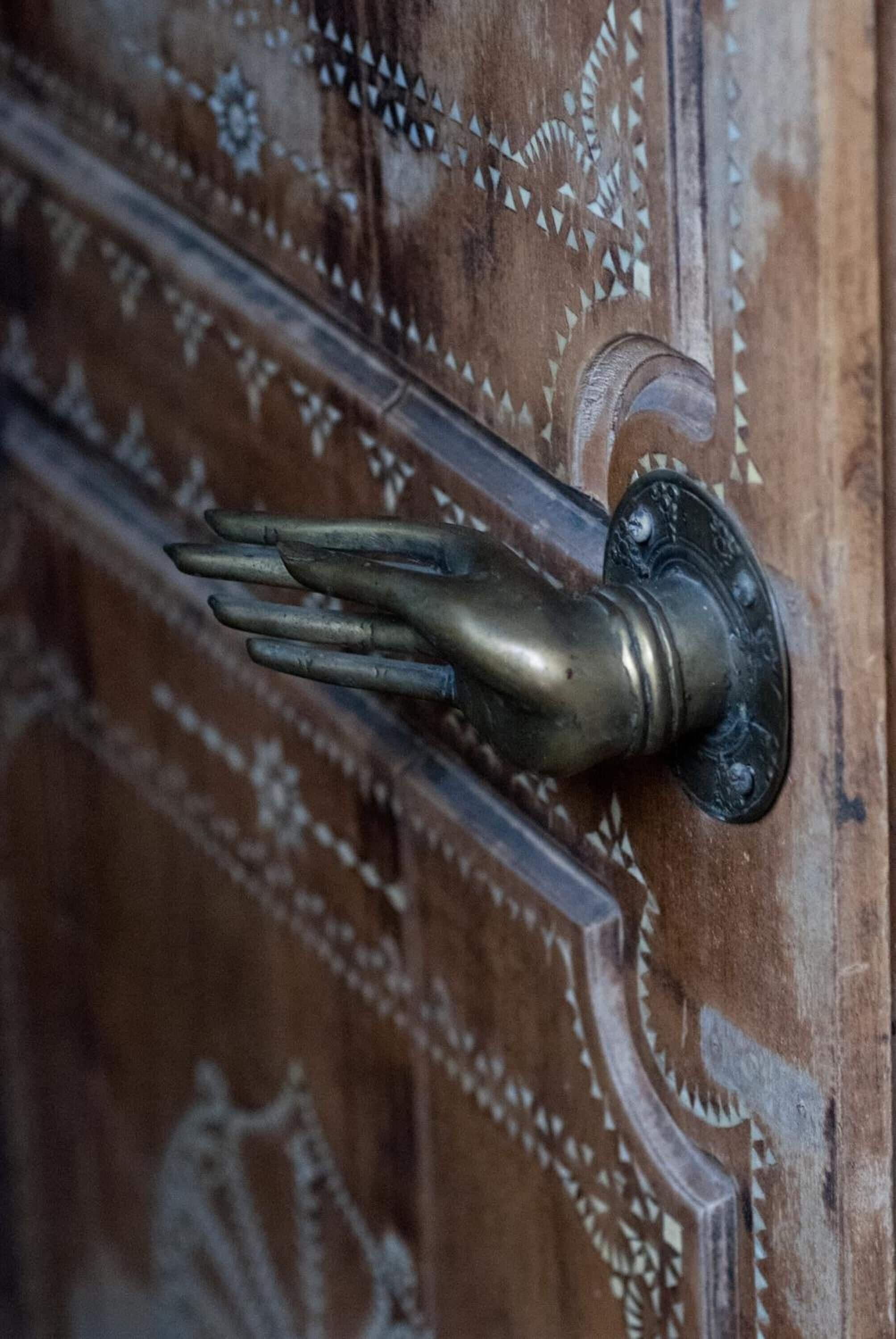 A wooden door with intricate carvings and a brass door handle.