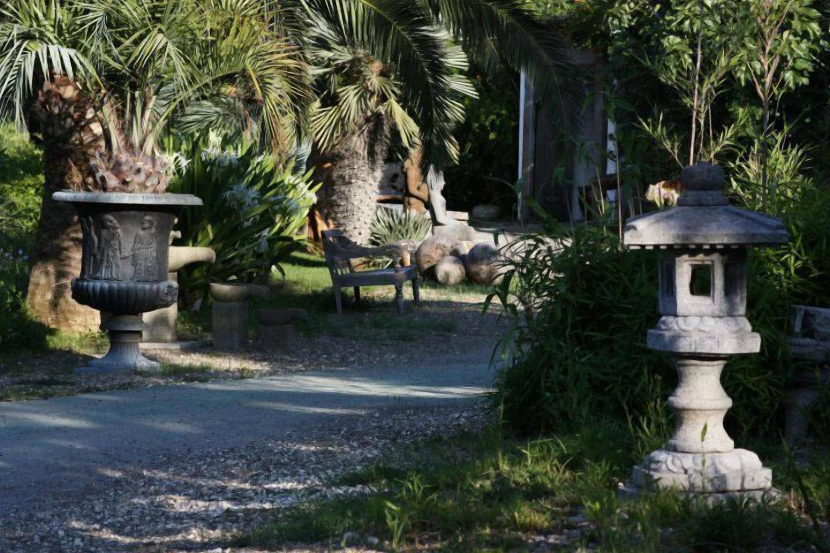 Ein Garten mit Steinbeeten, einer Bank und einem Weg.