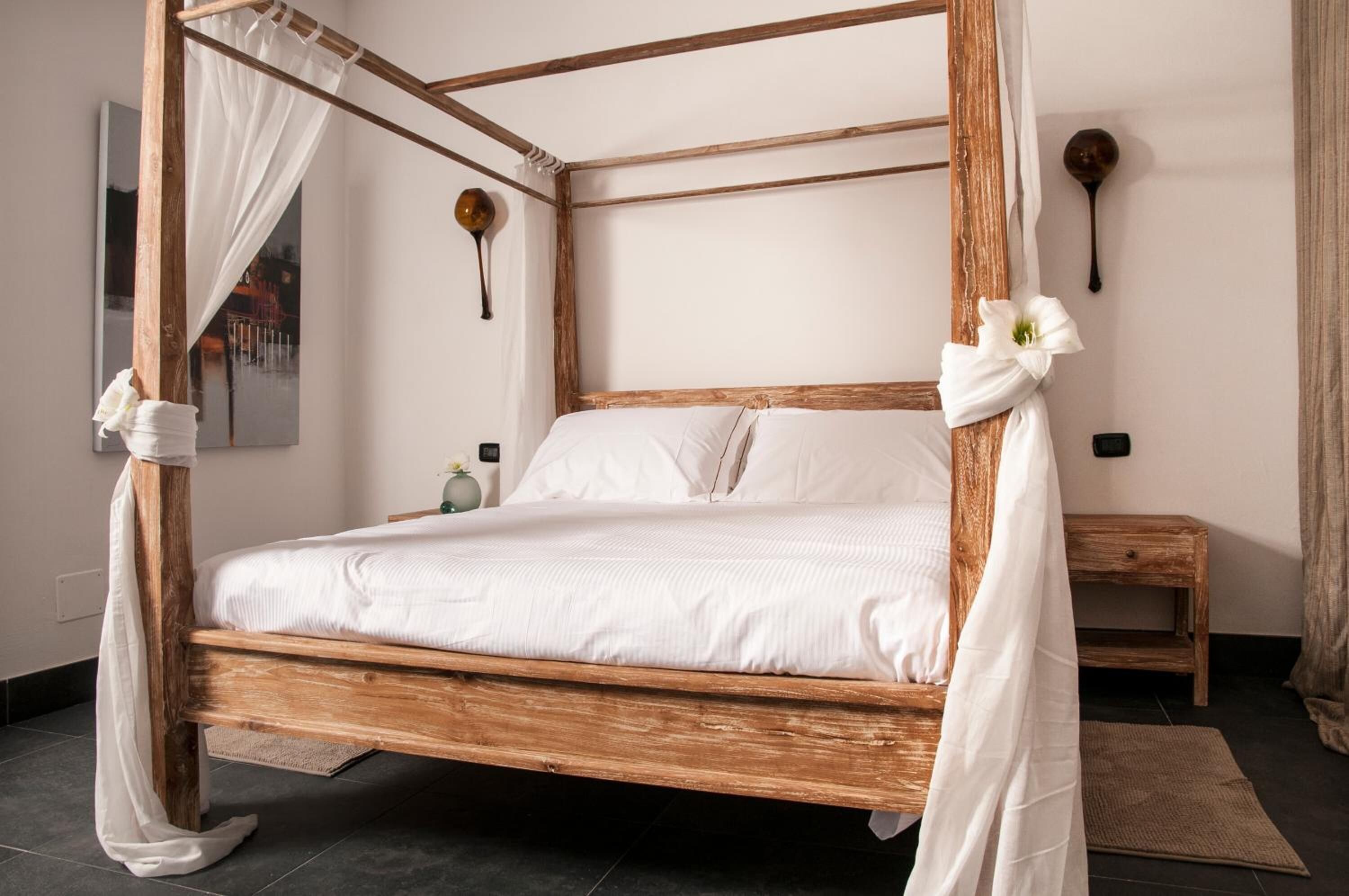 Ein Bett mit Himmelbett, ausgestattet mit weißen Leinen, einem Holzrahmen und einem weißen Baldachin.