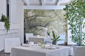 Un comedor con manteles blancos, cristalería y orquídeas.