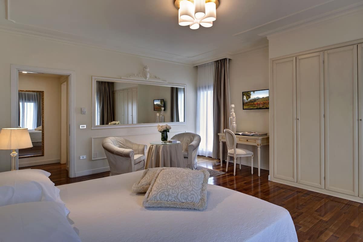 Una habitación de hotel con una cama grande, un escritorio, una silla, un espejo y un armario.