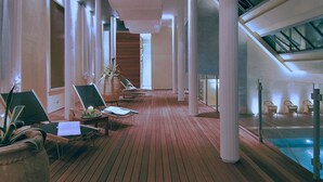 A spacious indoor area with wooden flooring, multiple lounge chairs, and a pool area. - Europa Terme (Abano Terme)